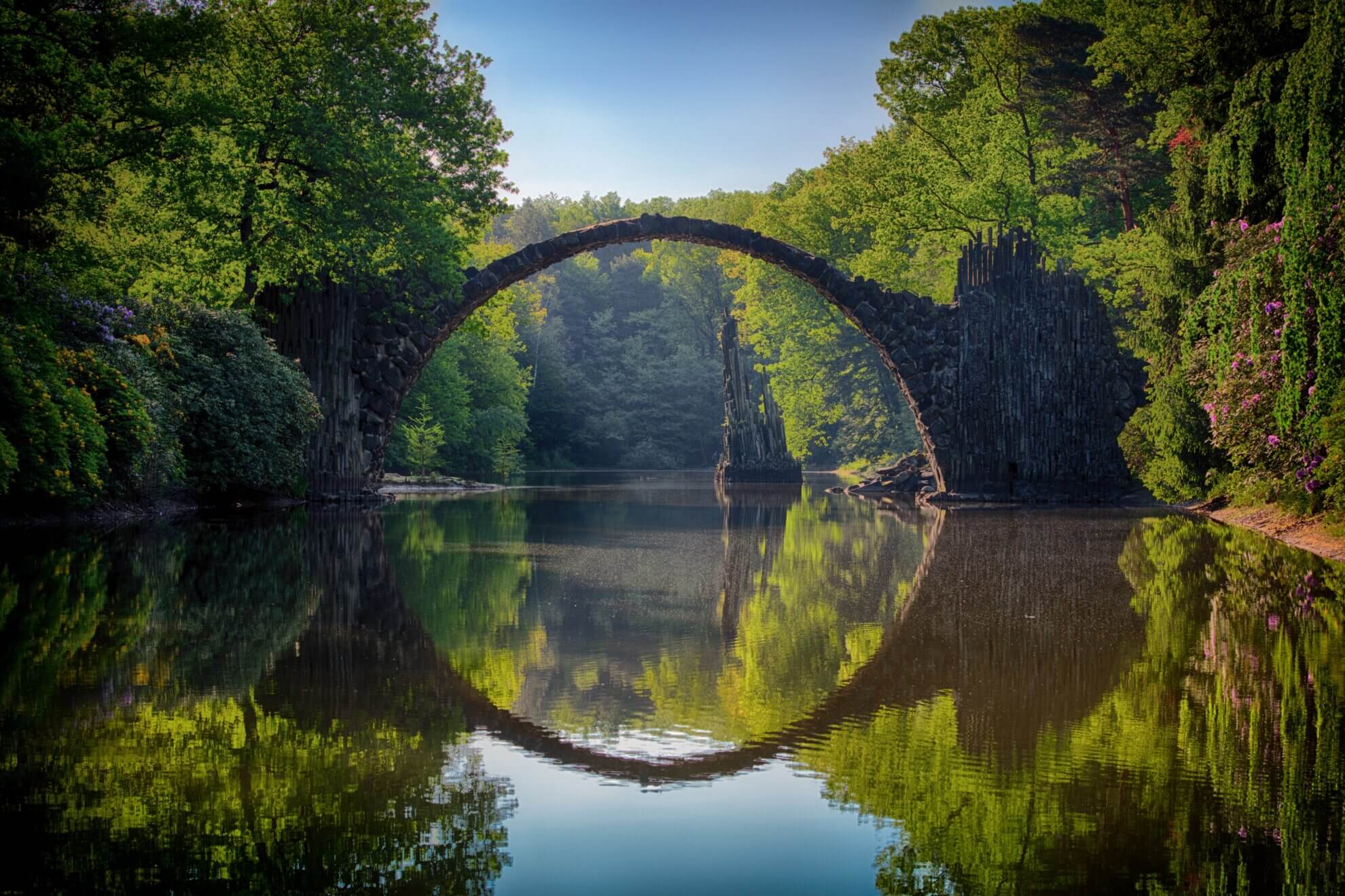 Alte Steinbrücke die über einen ruhigen Fluss führt. Symbolisch für die klassischen Übergangsrituale.