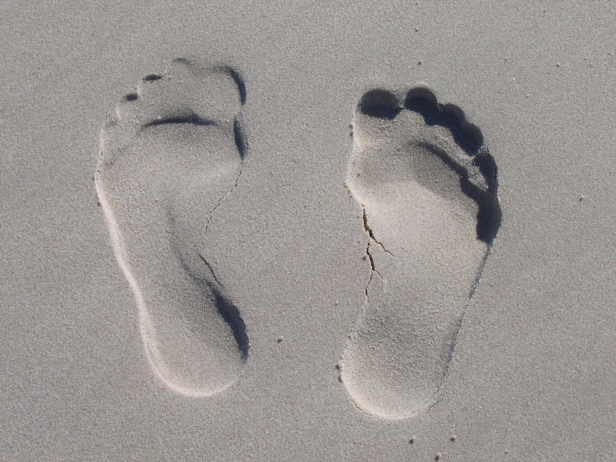 Fußabdrücke im Sand. Symbolisch für für das Impressum, das Eingedruckte/Aufgedruckte